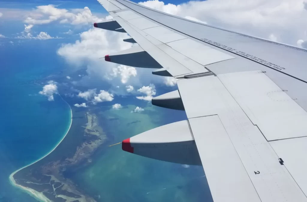 Airplane wing above a tropical coastline, these wings could fly.